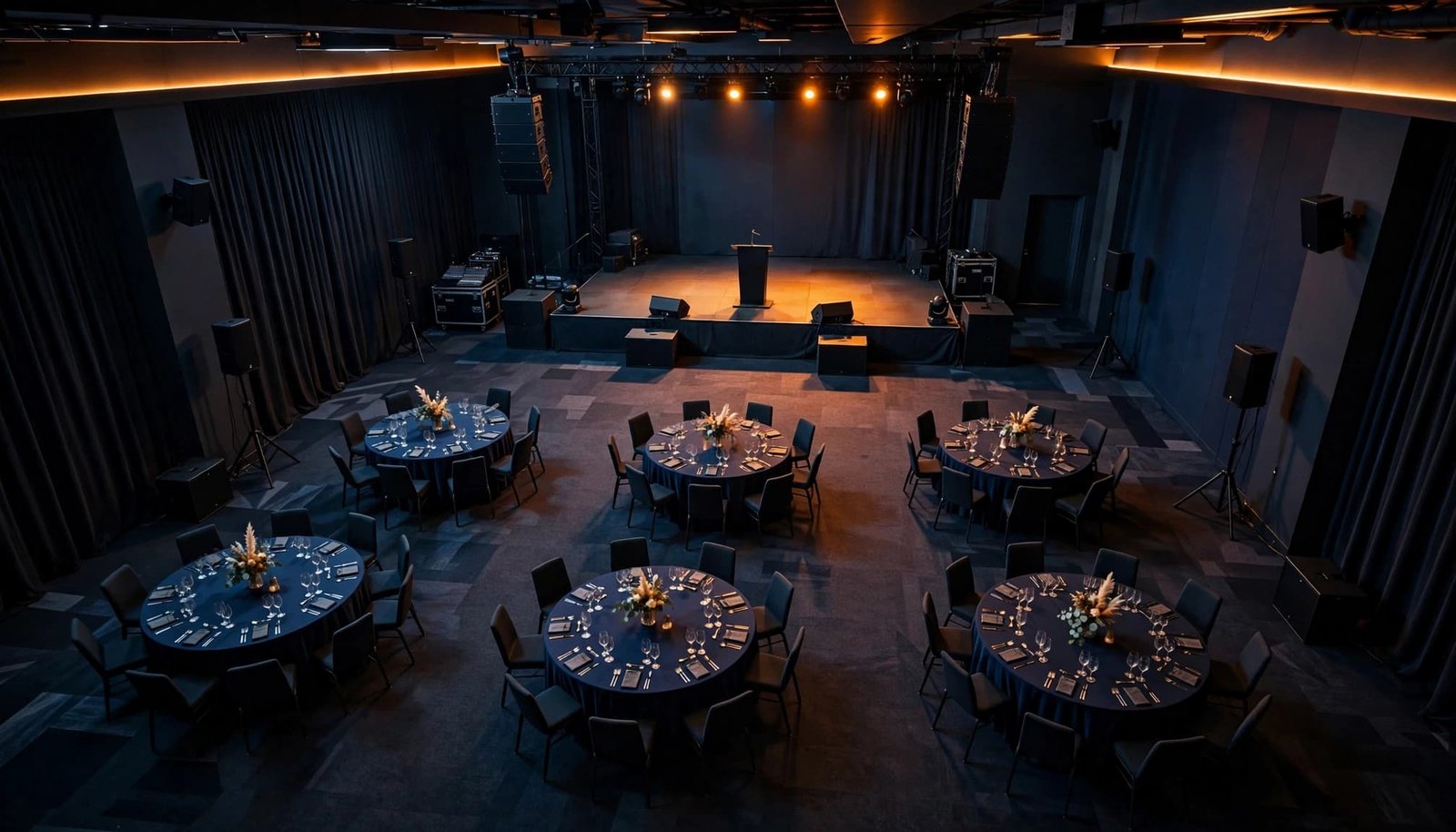 Corporate Event Seating Plans That Help Music Reach Every Guest Empty ballroom with a stage, six tables, wide aisles, and speakers.
