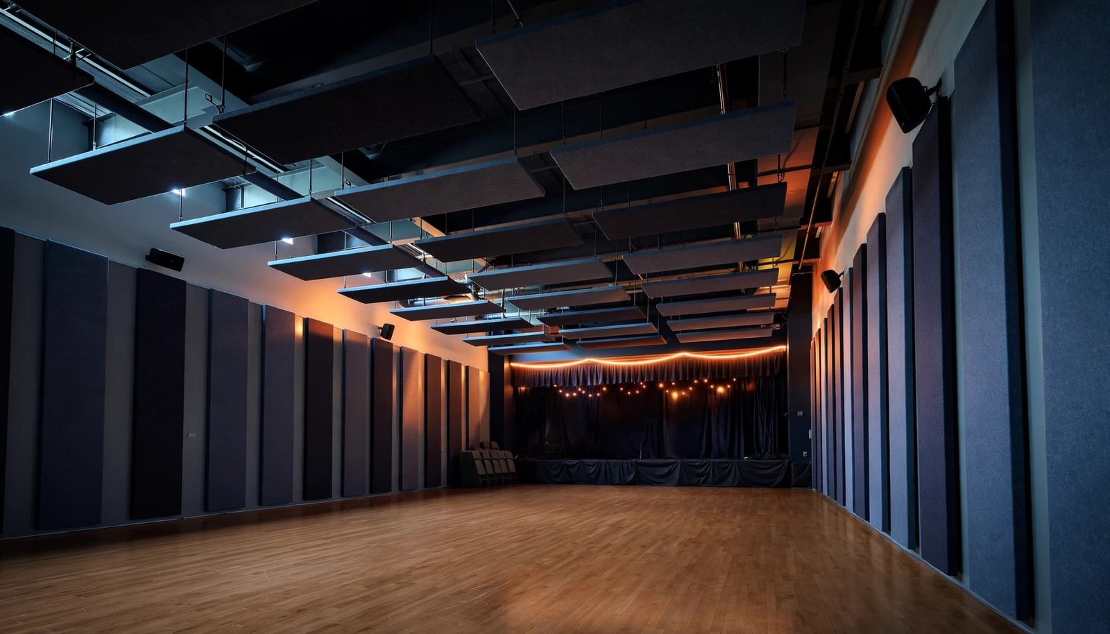 A school gym with ceiling clouds, wall panels, and a polished hardwood floor.