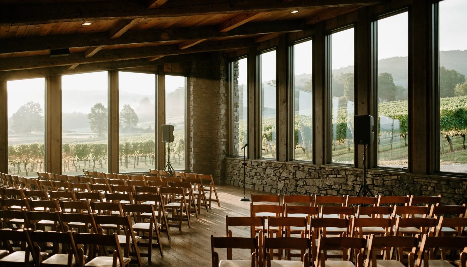 An empty winery reception room set up with rows of chairs, a microphone on a stand, and speakers.